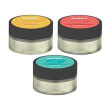 Load image into Gallery viewer, Three round containers of Sensi Skin 100mg CBD Sugar Lip Scrub. The top-left container is Honey-flavored with a yellow lid, the top-right is Strawberry-flavored with a red lid, and the bottom container is Peppermint-flavored with a green lid. Each vegan-friendly 25g container features a black band around the lid. (BUY 1 GET 1 FREE)